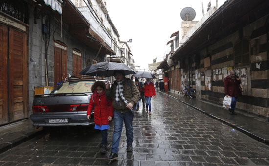 الأطفال يحتمون بالمظلات من الأمطار فى دمشق