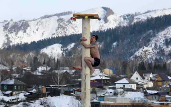 أحد المواطنين يتسلق عمود خشبى للحصور على جائزة