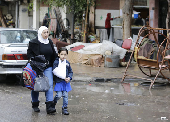 أم سورية توصل ابنتها المصابة إلى المدرسة بدمشق