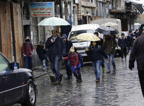 الطلاب السوريين يحملون المظلات فى طريقهم للمدارس