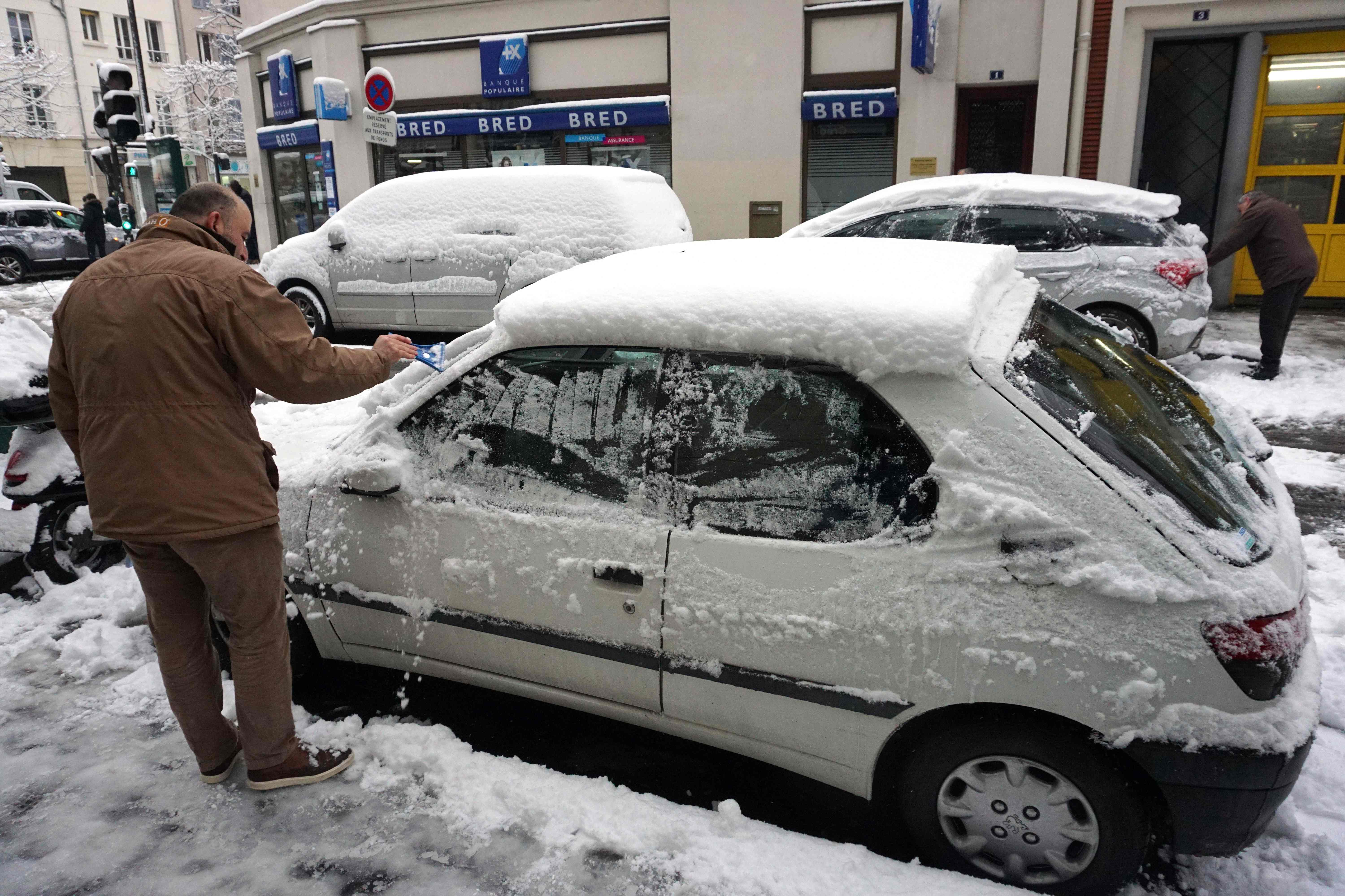 مواطن فرنسى يزيل طبقات الثلوج من على زجاج سياراته