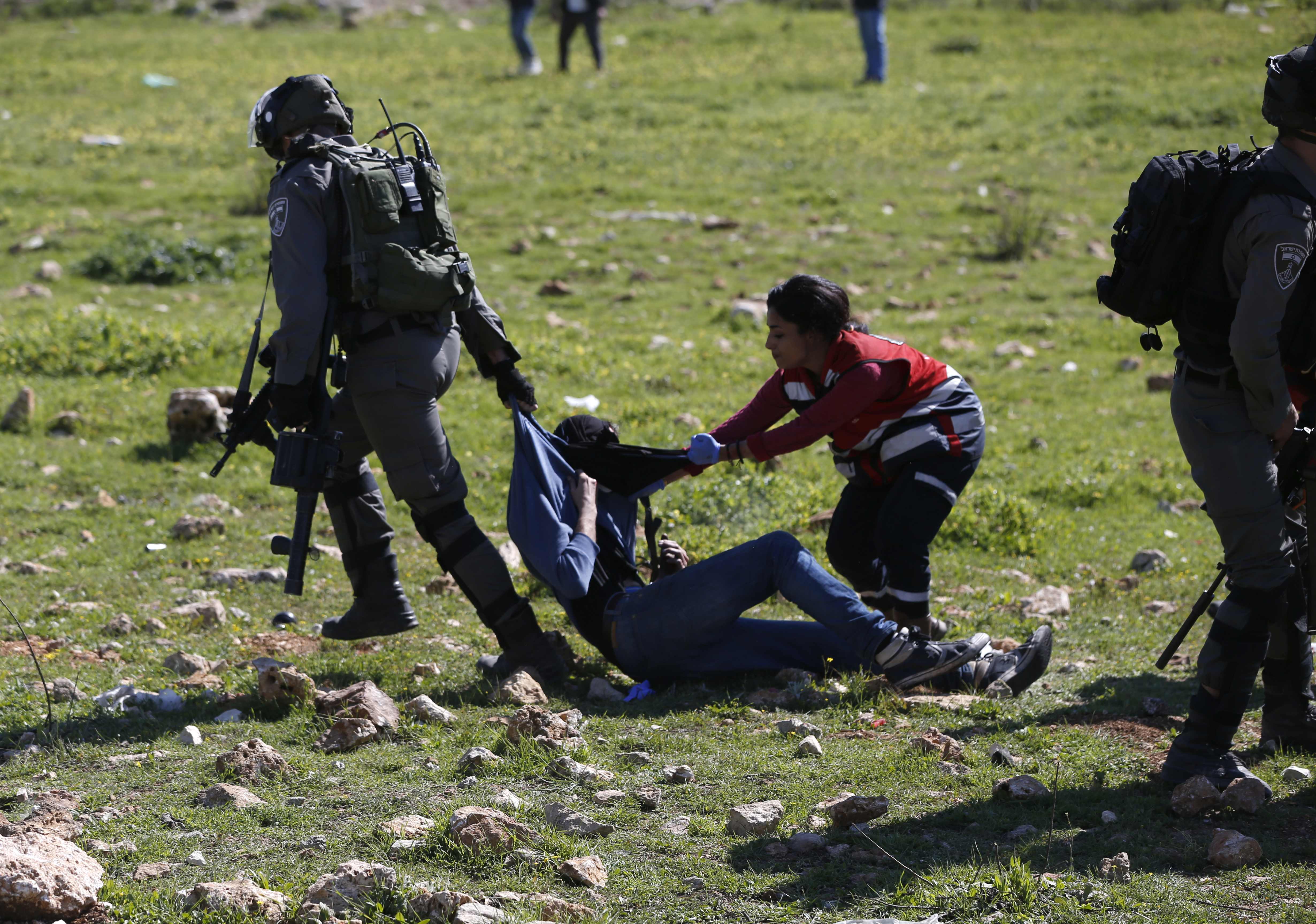 إحدى العاملات فى الاسعاف تحاول انقاذ الشاب الفلسطينى من يد الاحتلال