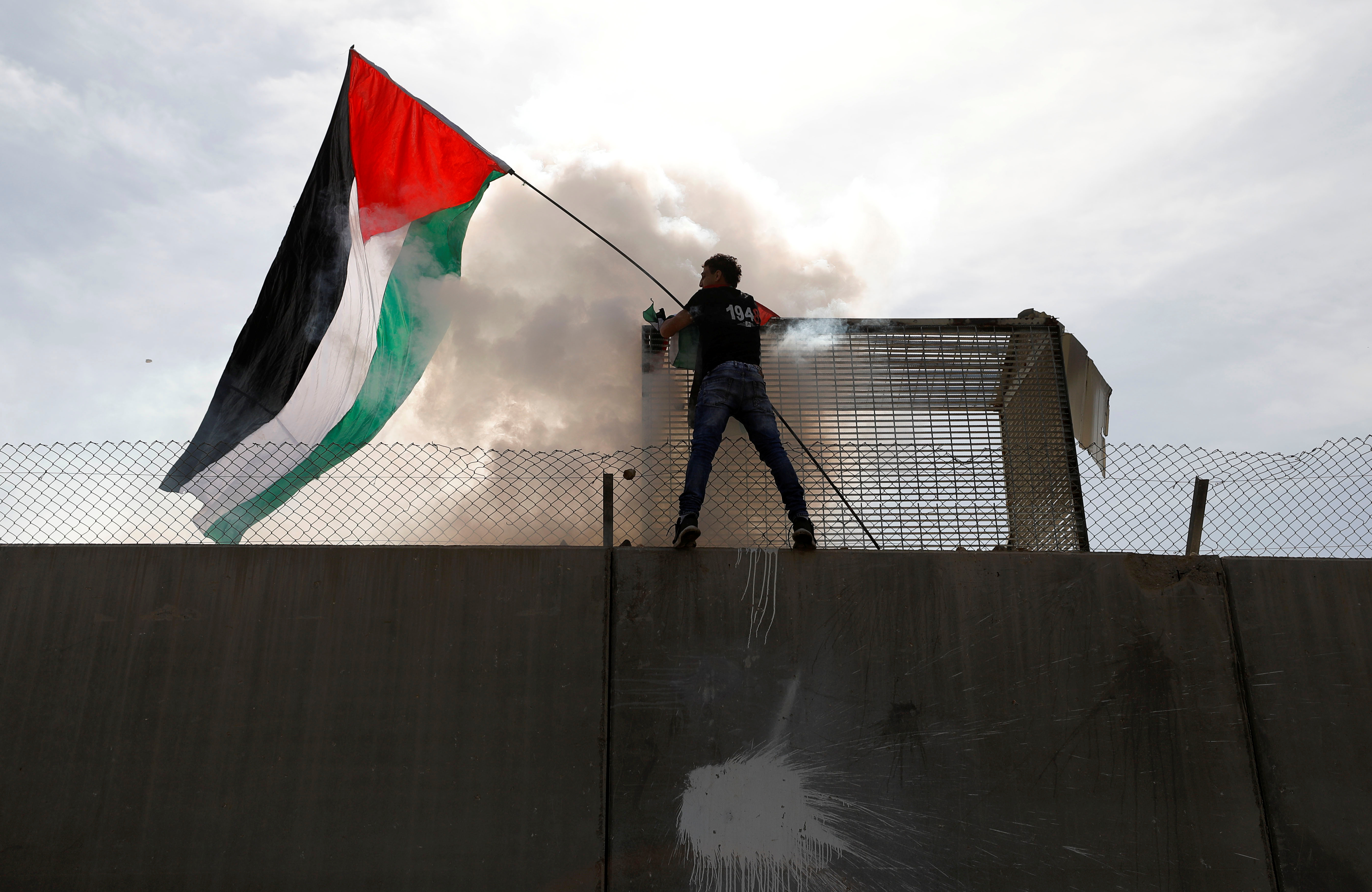أحد الفلسطينيين يعتلى الجدار العازل