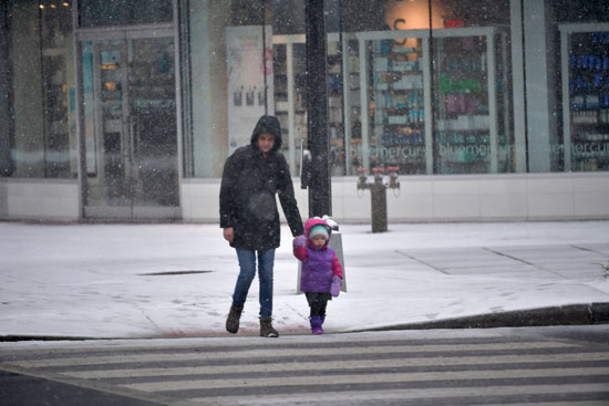 أم وابنتها يعبران الطريق فى ظل العاصفة الثلجية