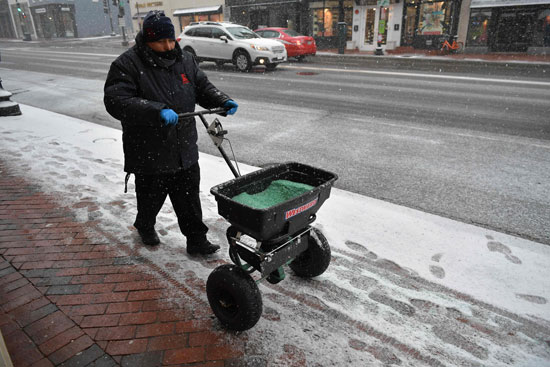 عامل يدفع عربته وسط العاصفة الثلجية فى واشنطن