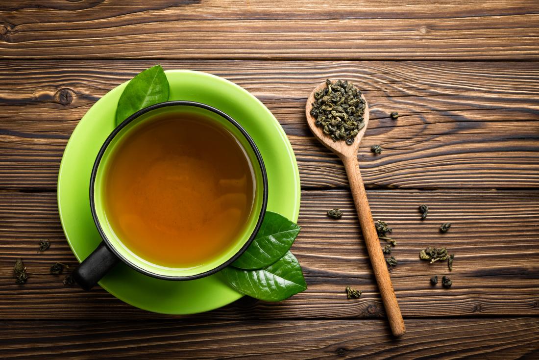 green-tea-in-cup-with-tea-leaves-on-wooden-spoon