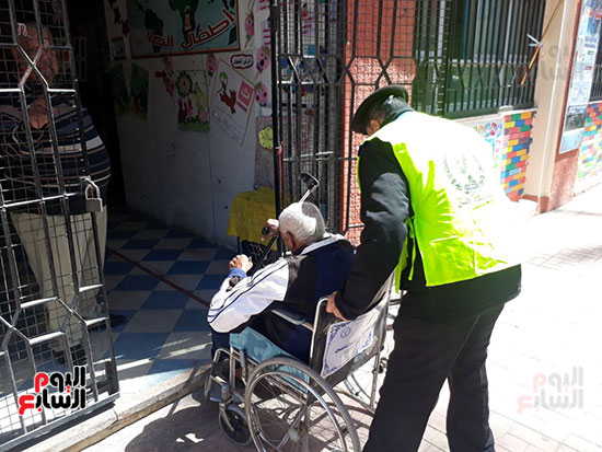 رجل شرطة يساعد رجل مسن للدخول للجنته الانتخابية