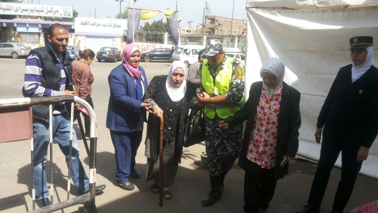رجال الشرطة تساعد مسنة الوصول لمقر لجنتها الانتخابية  (1)