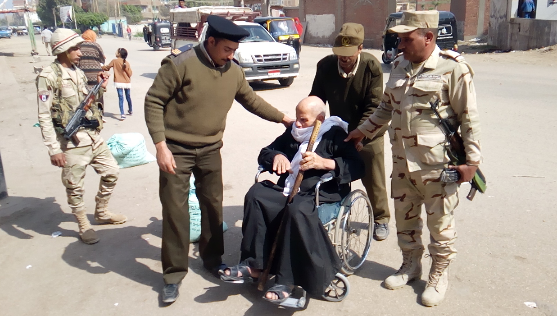 صور على كرسي متحرك رجال الجيش يساعدون مُسن للإدلاء بصوته  بمنيا القمح (1)