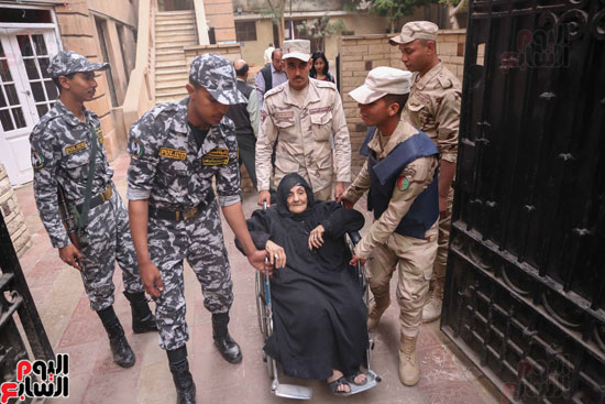 قوات تأمين اللجان تحمل مسنتين للإدلاء بأصواتهما فى القاهرة (8)