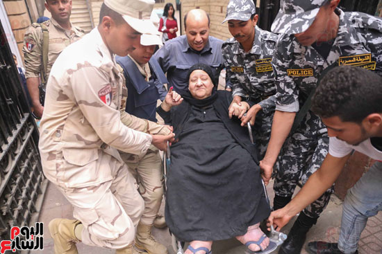 قوات تأمين اللجان تحمل مسنتين للإدلاء بأصواتهما فى القاهرة (4)