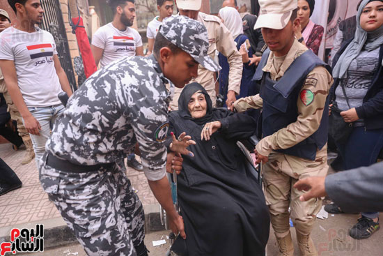 قوات تأمين اللجان تحمل مسنتين للإدلاء بأصواتهما فى القاهرة (9)