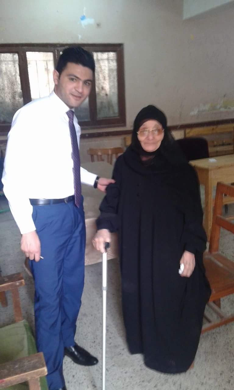 رئيس لجنة مدينة ههيا  يساعد ناخبة مسنة في الأداء بصوتها (1)