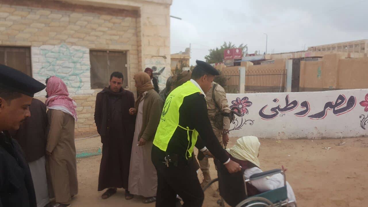 شرطى يساعد ناخب مسن عقب الادلاء بصوته