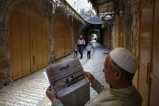 رجل فلسطينى يقرأ الجريدة فى الشارع أثناء الإضراب الشامل