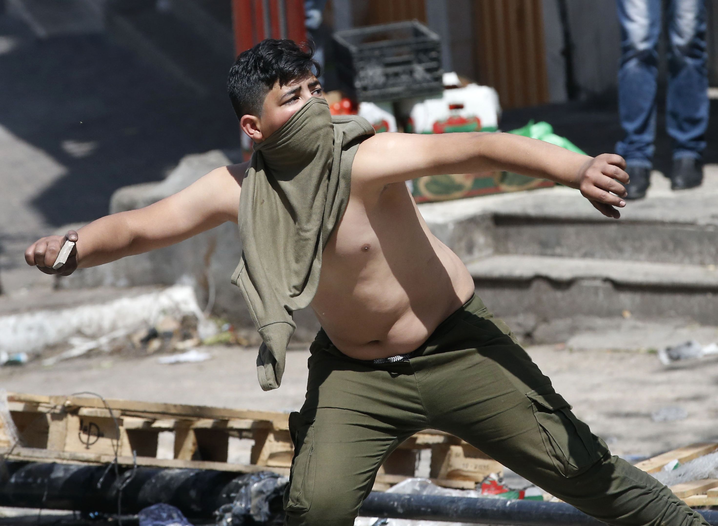فلسطينى يرشق قوات الاحتلال بالحجارة