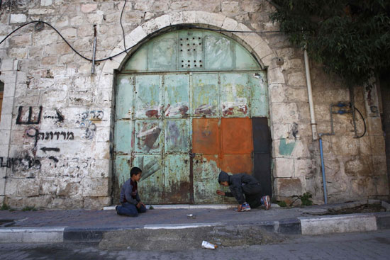 أطفال فلسطينيون يعلبون أمام المحلات المغلقة بسبب الإضراب