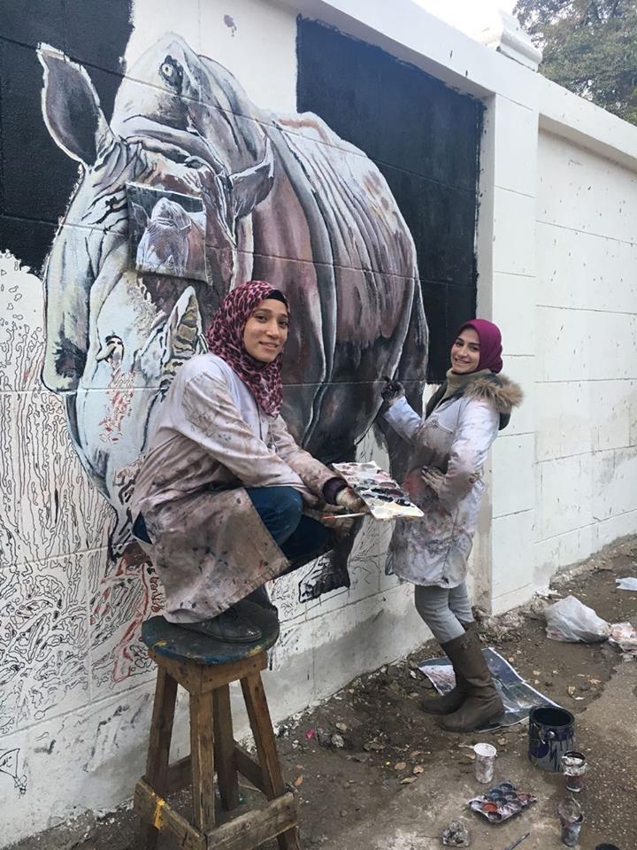 الفتيات أثناء الرسم على جدار حديقه الحيوان