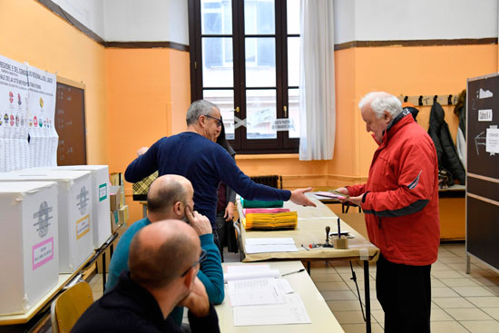 مراقب يطلع على أوراق ناخب بالانتخابات التشريعية الإيطالية
