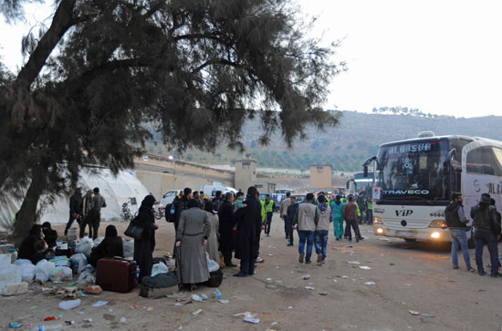 عدد من السوريين فى انتظار ركوب الحافلات لمغادرة دوما