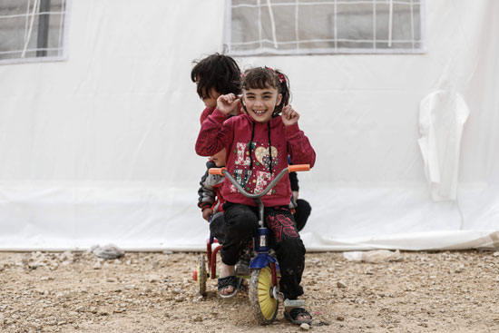 طفل سورية تلعب بدراجتها داخل مخيم للاجئين