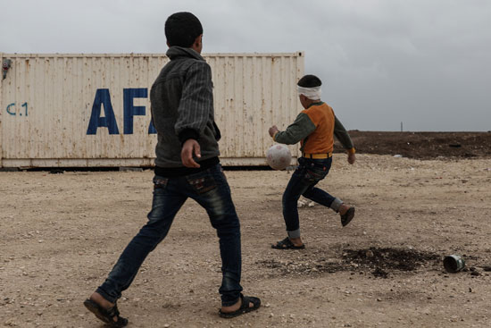 طفلان سوريان يلعبان كرة القدم داخل مخيم للاجئين