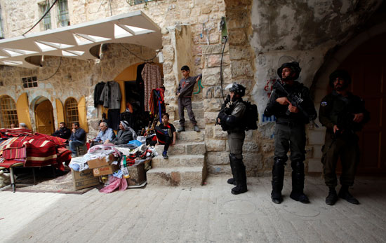 التجار الفلسطينيين يجلسون أمام متاجرهم عقب إغلاقها