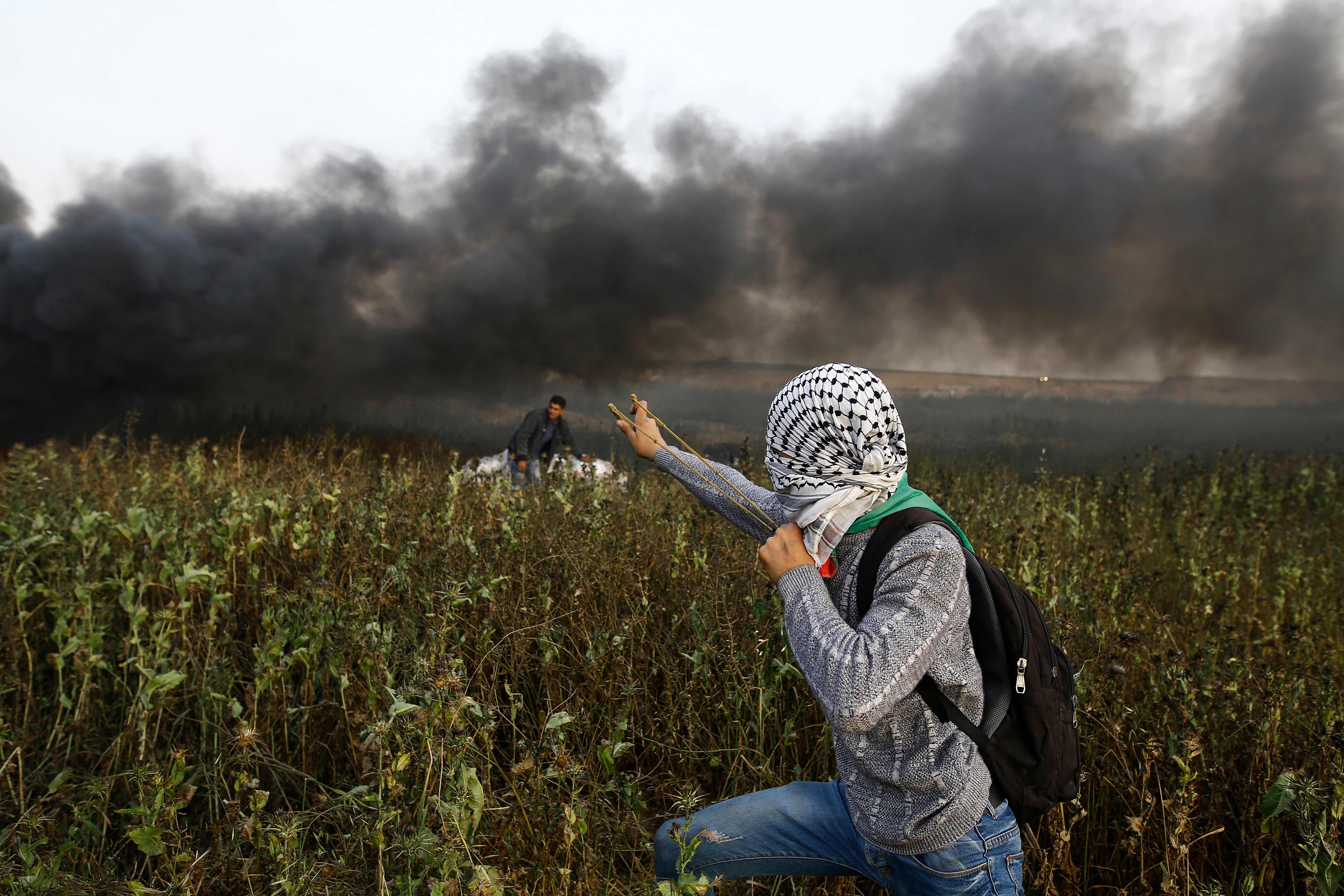 فلسطيني يطلق الحجارة
