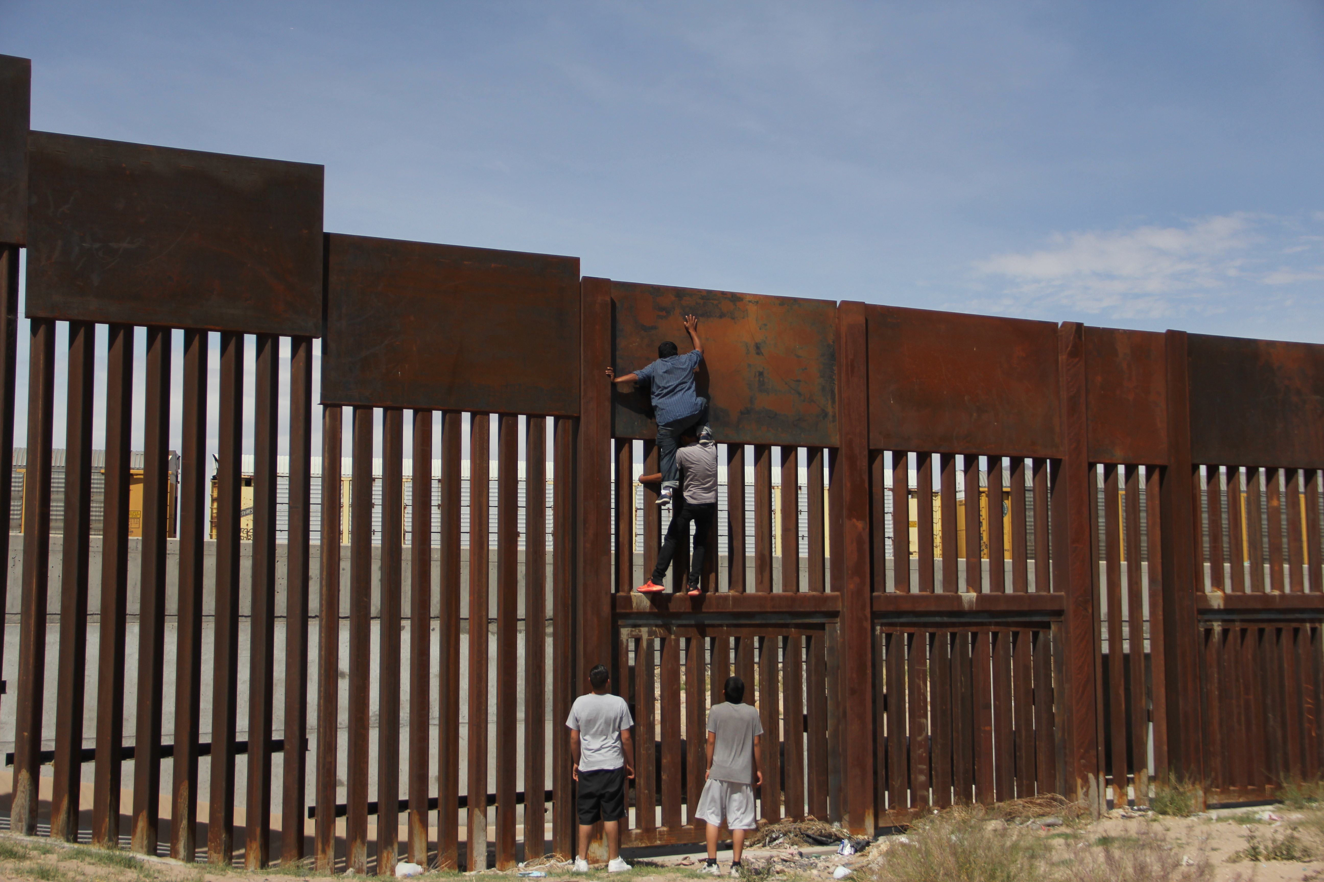 شباب يعبر الجدار الحدودى بين المكسيك وأمريكا
