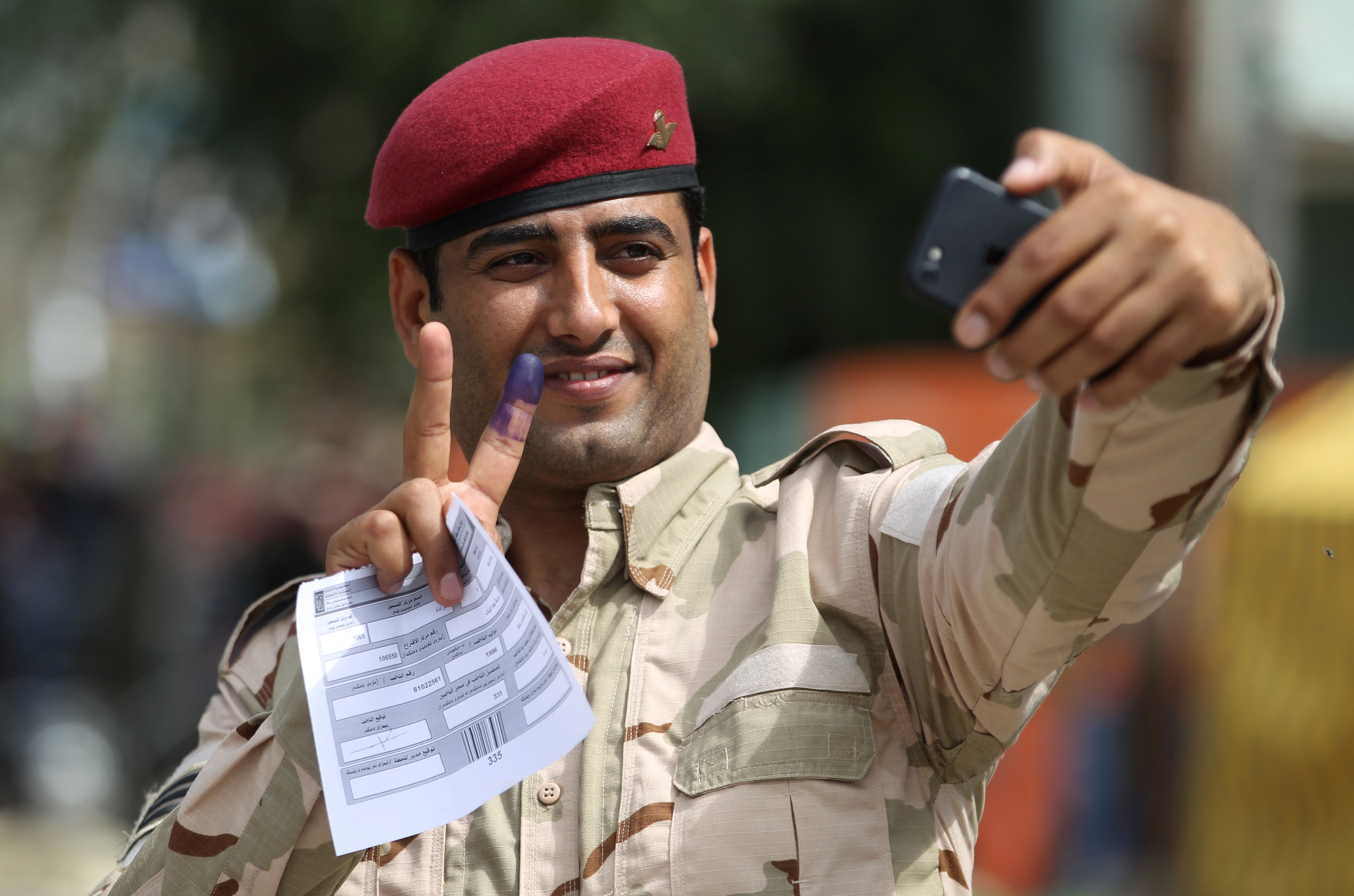 أحد جنود الجيش العراقى يرفع علامة النصر بعد مشاركتة فى الانتخابات