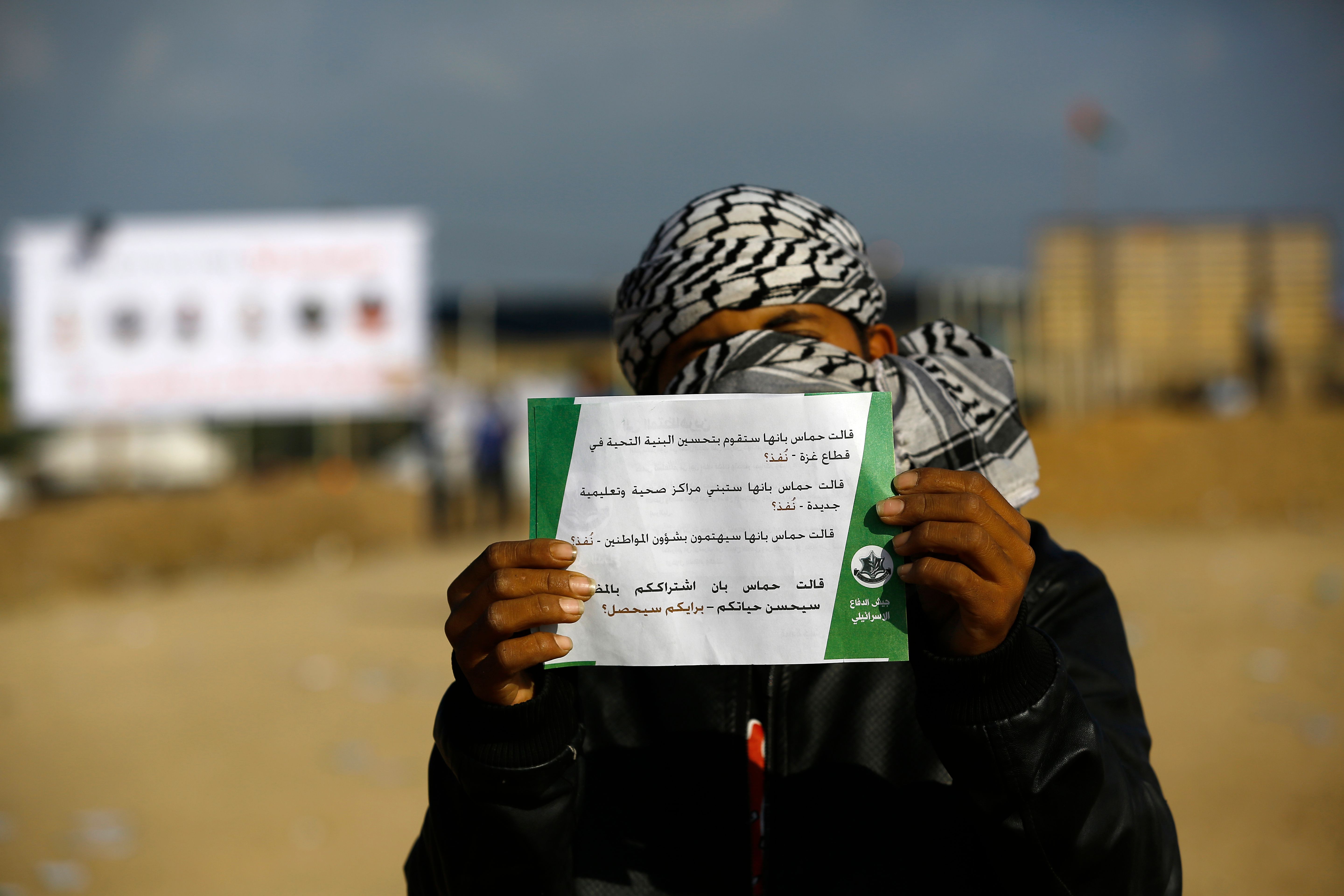 شاب فلسطينى يحمل منشور تحذيرى من الاحتلال الإسرائيلى