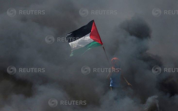 فلسطينى يرفع علم بلاده فى مواجهة الاحتلال بقطاع غزة