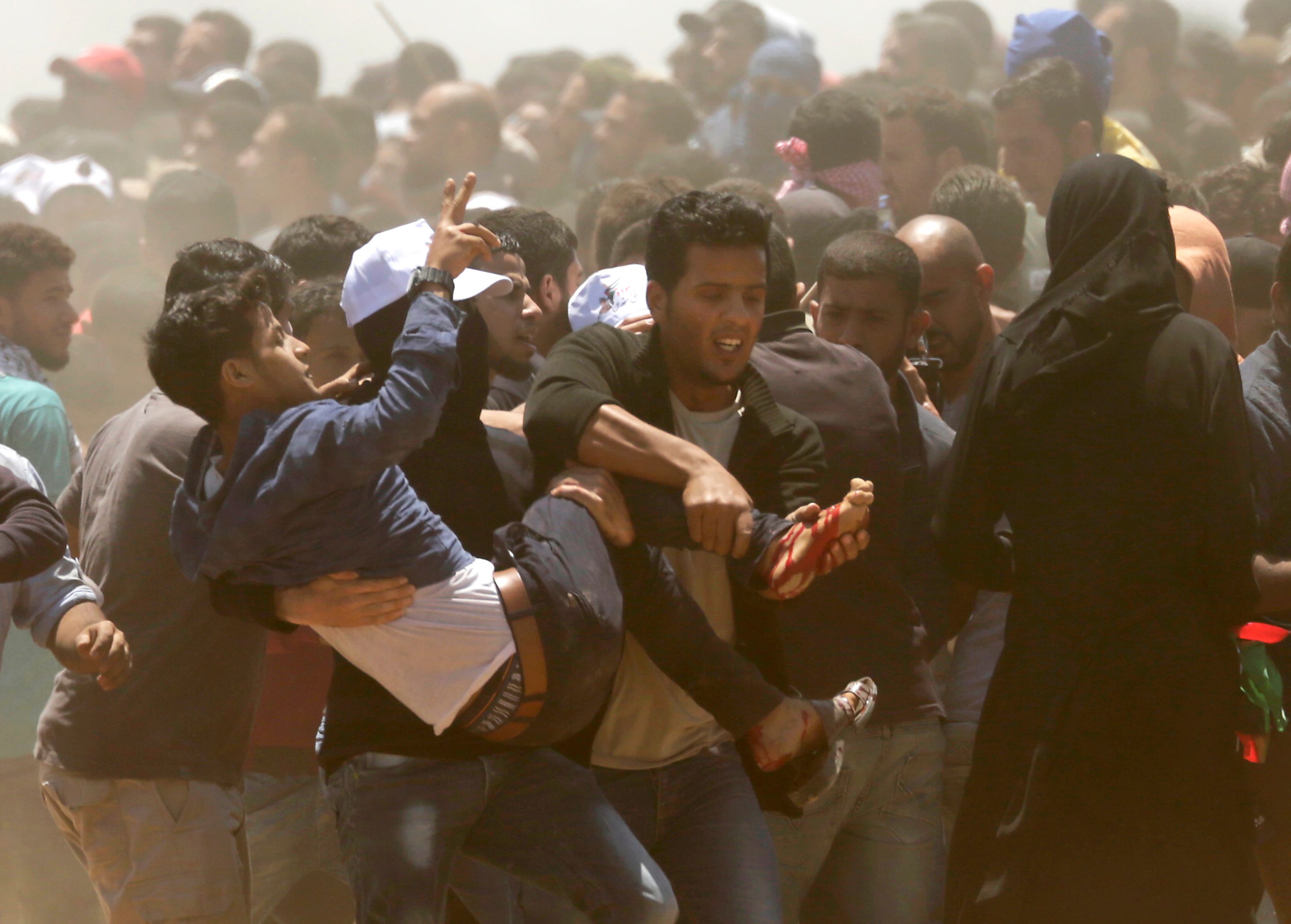 شباب فلسطينيين يحملون صديقهم المصاب فى مواجهة الاحتلال