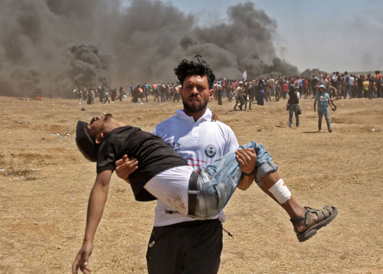 شاب فلسطينى يحمل صديقه المصاب برصاص الاحتلال