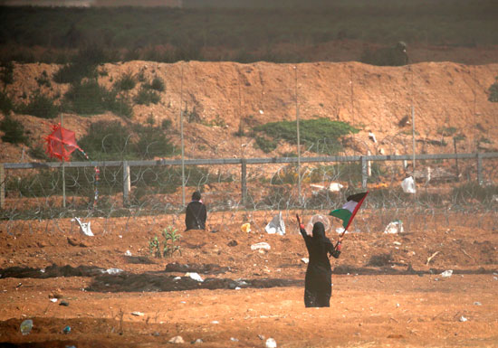 سيدة فلسطينية ترفع علم بلادها فى مواجهة جنود الاحتلال