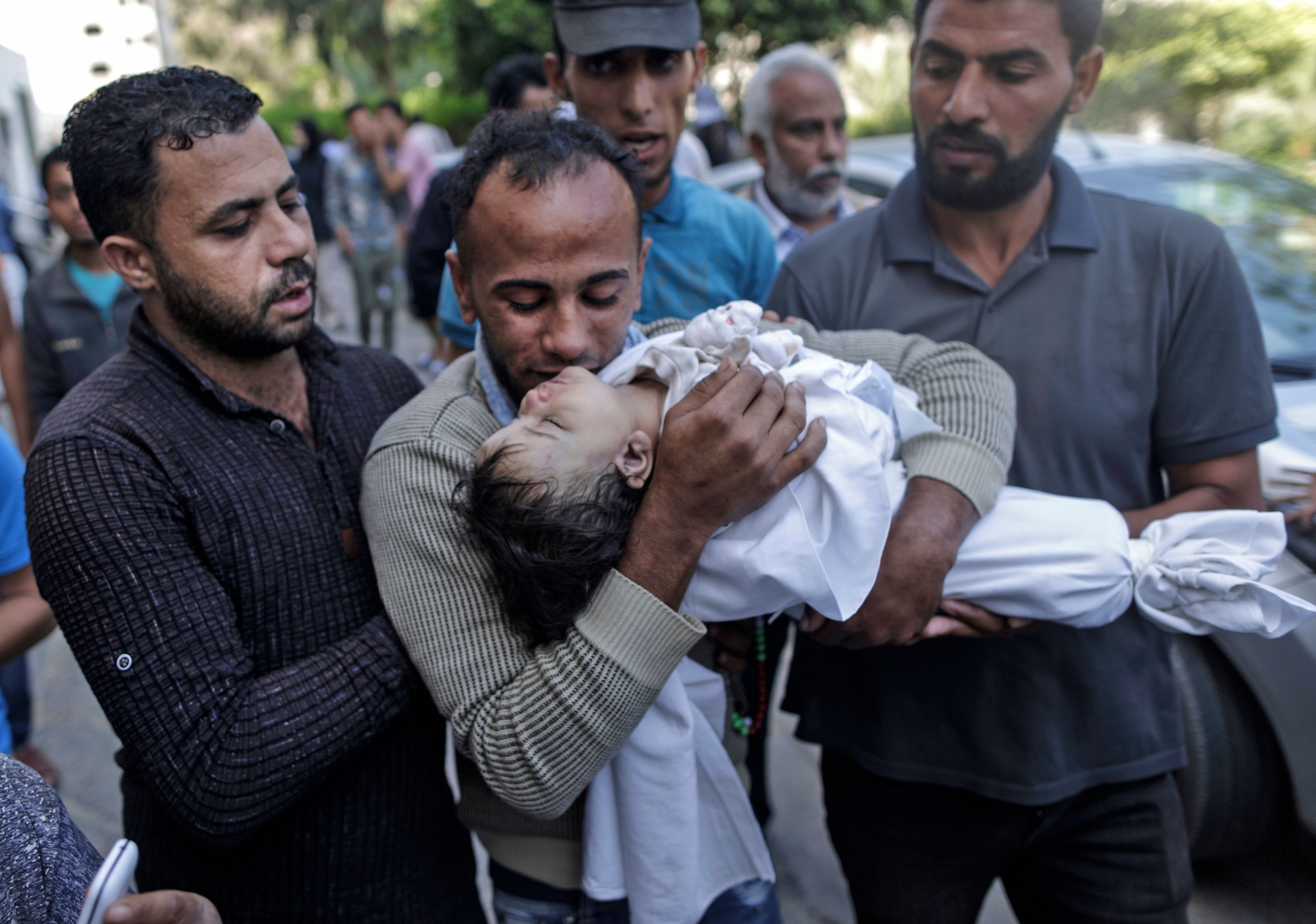 رجل فلسطينى يقبل رأس الطفلة الشهيدة