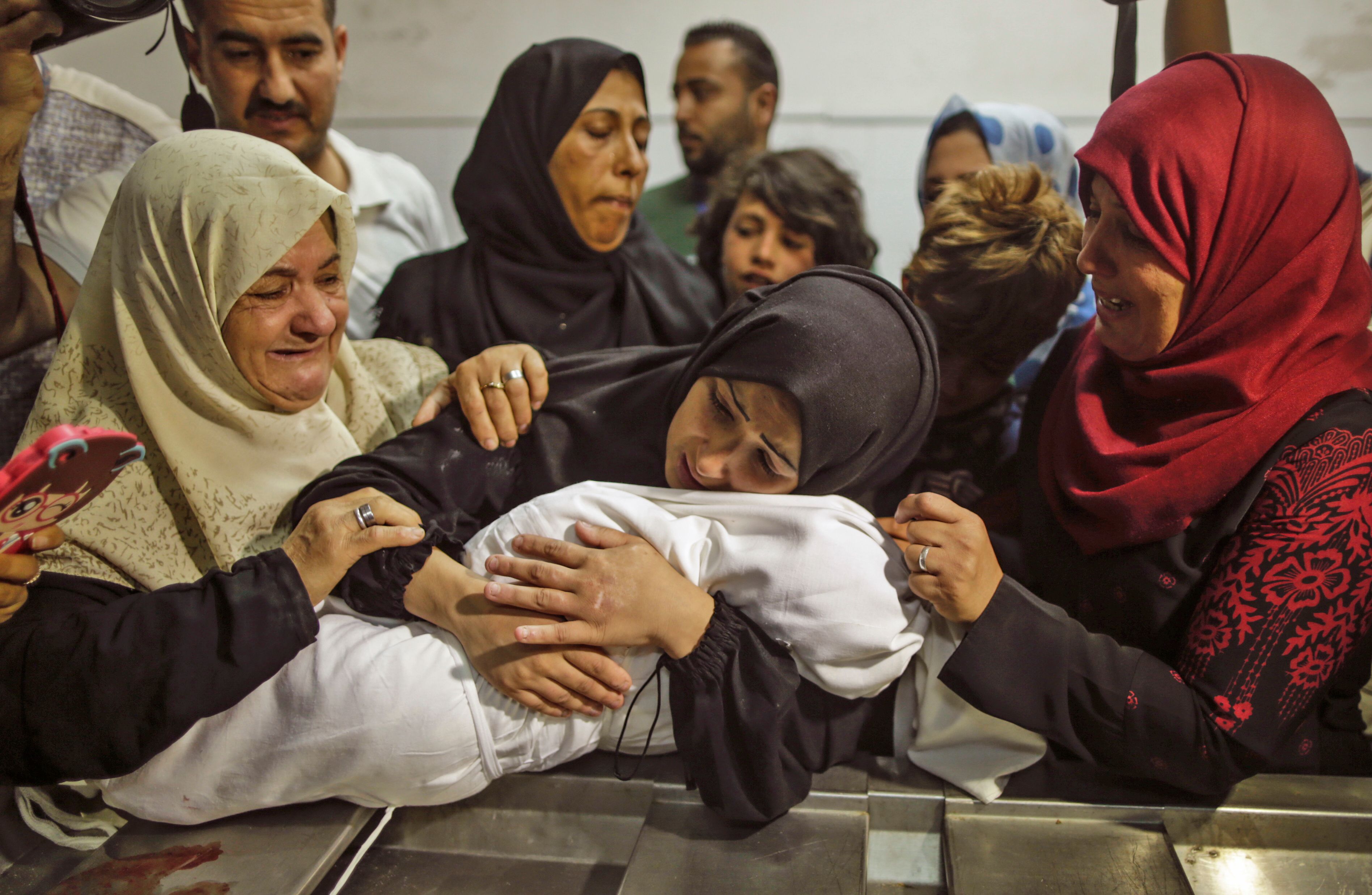 أم الطفلة الشهيدة تحتضنها قبل دفنها