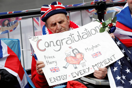 مواطن بريطانى يحمل لافتة تهنئة للأمير هارى وخطيبته بحفل الزفاف