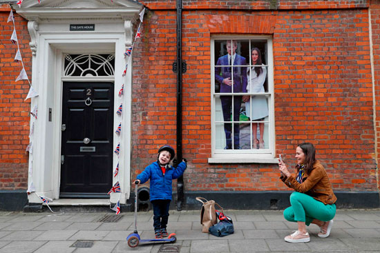 سيدة بريطانية تلتقط صورة لابنها مع صورة الأمير هارى وخطيبته