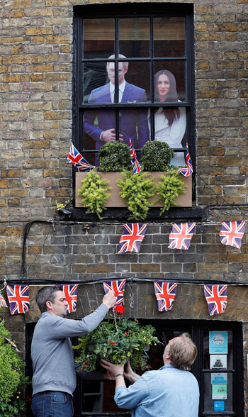 بريطانيان يزينان واجهة منزل بأعلام بريطانيا وصور هارى وماركل