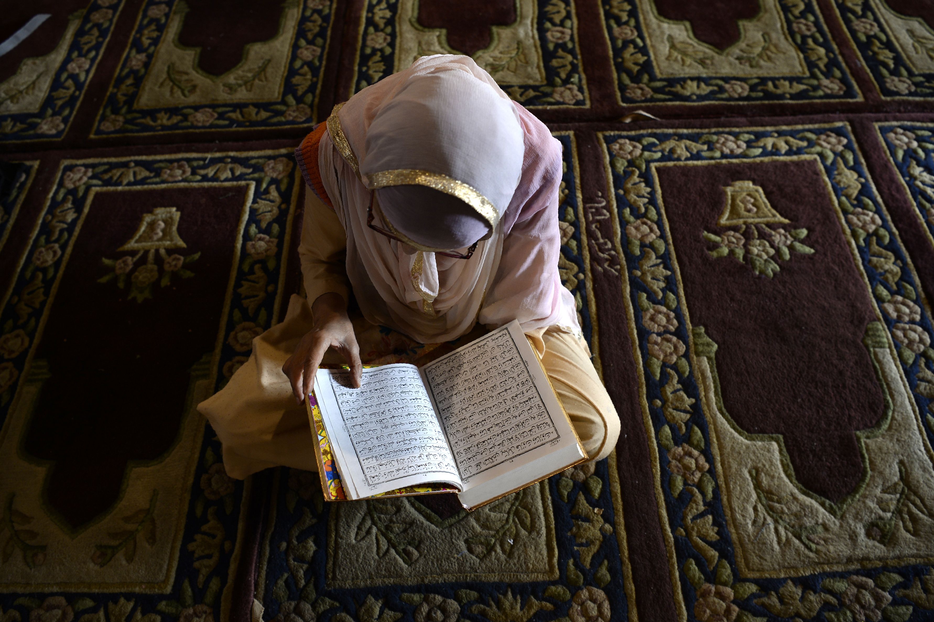 مسلمة كشميرية تقرأ القرآن