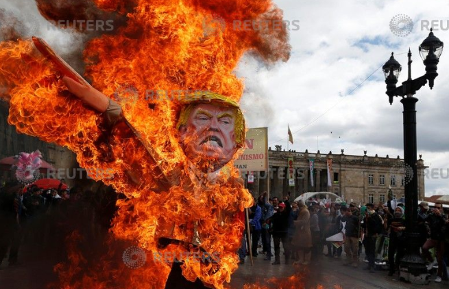 متظاهرون يشعلون النار فى صورة ترامب خلال احتفالات عيد العمال بكولومبيا