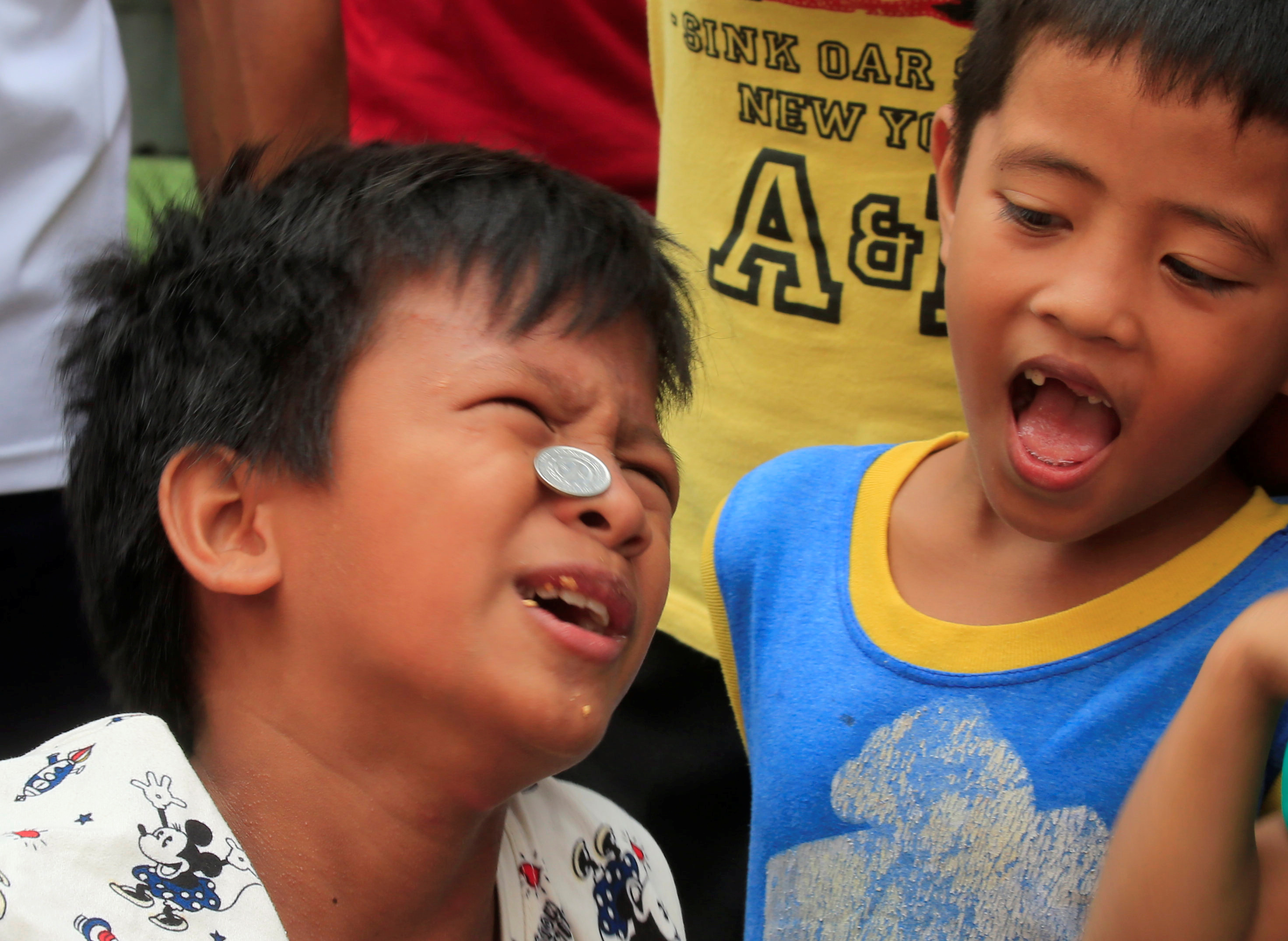 أحد الأطفال يحمل العملات المعدنية على وجهه لجلب الرزق خلال المهرجان
