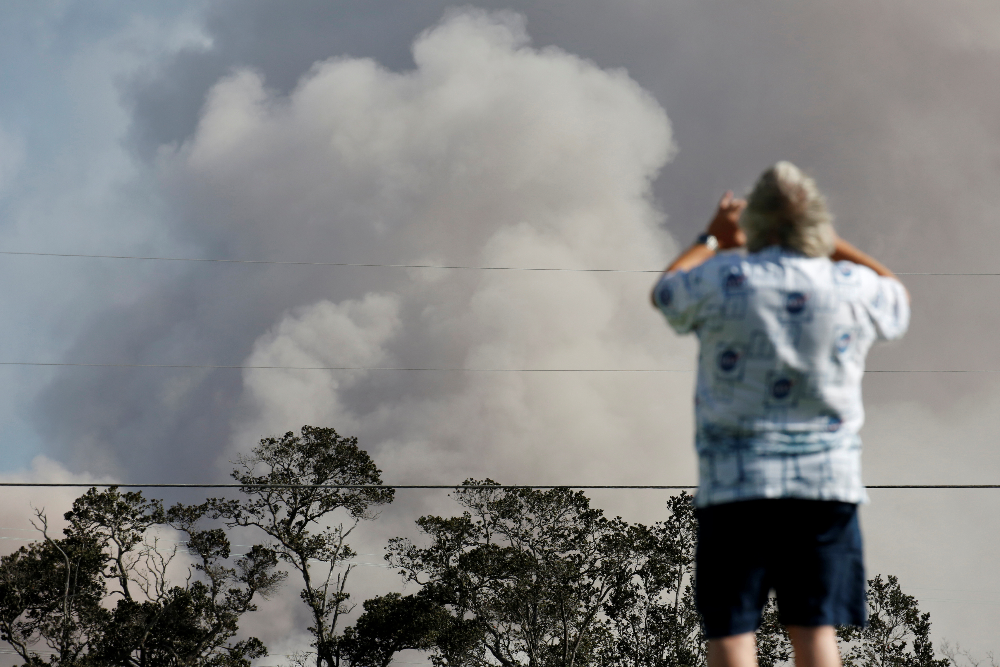 رجل يلتقط صورة للأدخنة المتصاعدة من البركان
