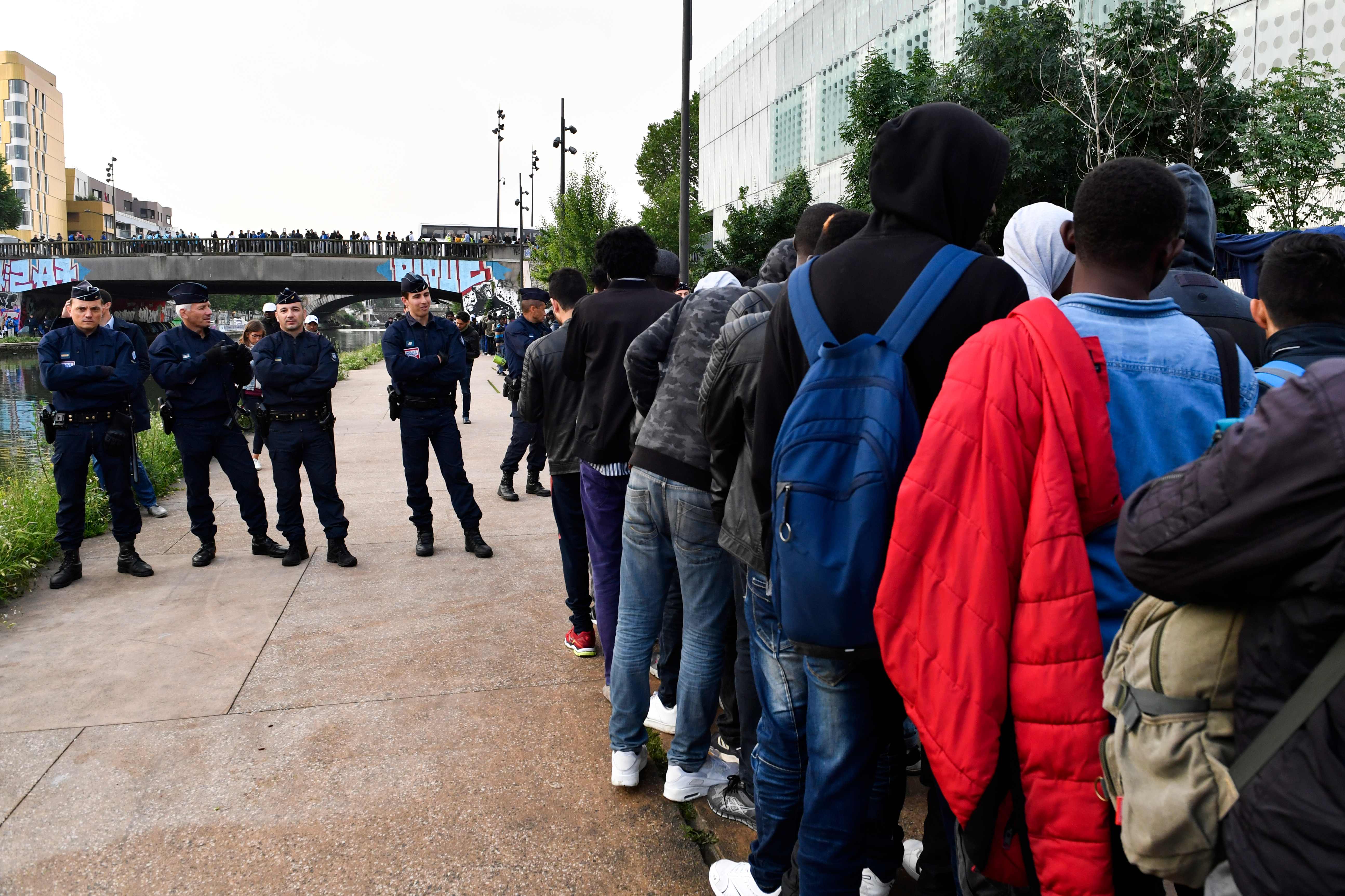 اصطفاف المهاجرين عقب اخلائهم من مخيمات بباريس
