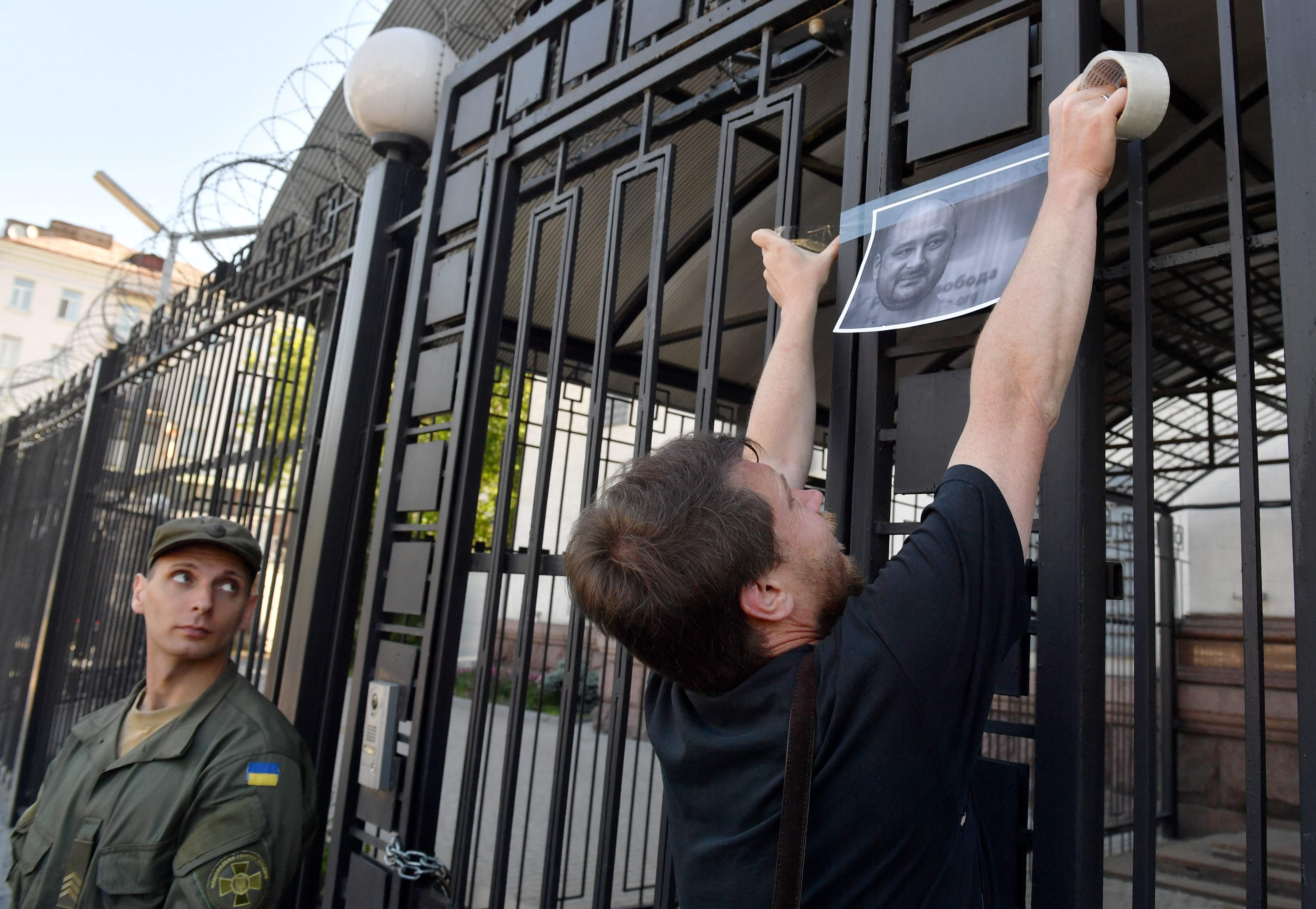 جندى أوكرانى يراقب تعليق صور صحفى مقتول على سور سفارة روسيا