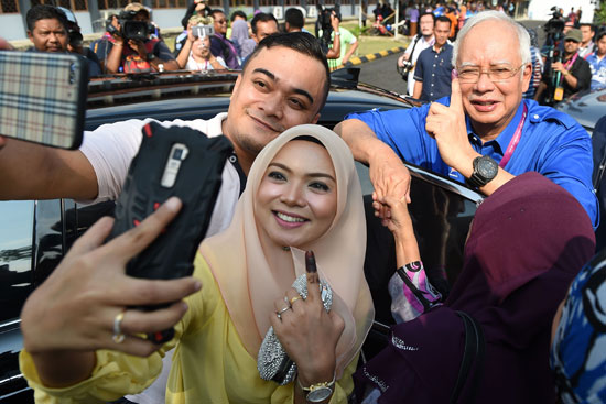 فتاة وشاب يلتقطان صورة سيلفى مع رئيس وزراء ماليزيا
