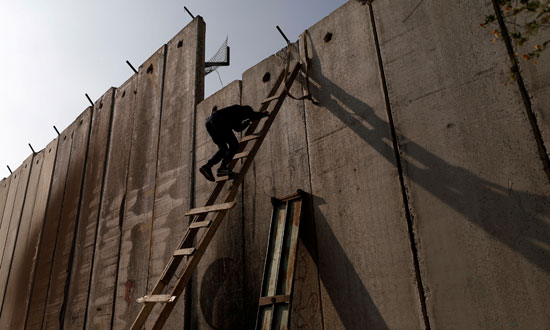 شاب فلسطينى يتسلق الجدار العازل للعبور إلى القدس المحتلة