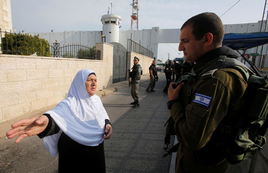 سيدة فلسطينية تقف أمام جندى إسرائيلى خلال عبورها نقطة تفتيش