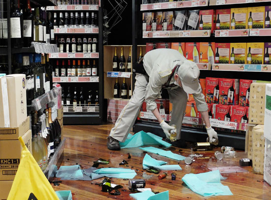  عامل متجر يجمع الزجاجات بعد الزلزال